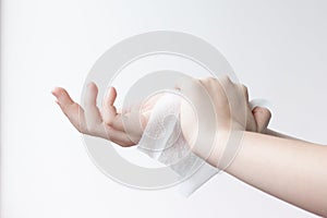 One hand wipes the other hand with a damp antibacterial cloth on a light background