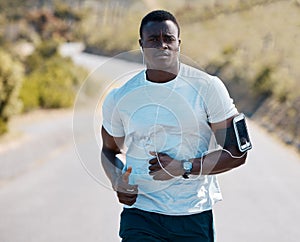 One handsome young african american athlete listening to music while out for a jog in nature. Dedicated black man