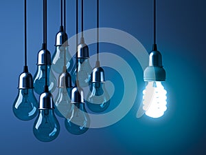 One hanging eco energy saving light bulb glowing and standing out from unlit incandescent bulbs