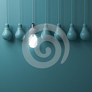 One hanging eco energy saving light bulb glowing and standing out from unlit incandescent bulbs