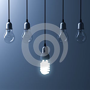 One hanging energy saving light bulb glowing different stand out from unlit incandescent bulbs
