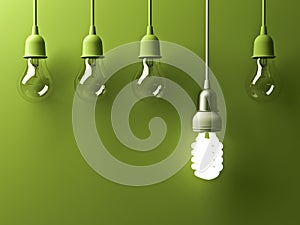 One hanging energy saving light bulb glowing different stand out from unlit incandescent lightbulbs