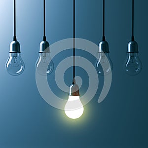 One hanging light bulb glowing different and standing out from unlit incandescent bulbs