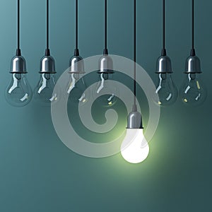 One hanging light bulb glowing different and standing out from unlit incandescent bulbs
