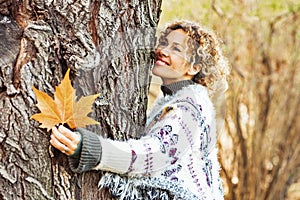 One happy adult woman hug a tree and smile in autumn season outdoor leisure activity. Natural lifestyle and love nature concept