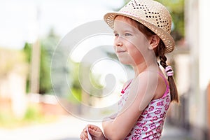 One happy cheerful joyful little girl alone, lone child in a sun hat smiling, portrait, copy space, lifestyle shot. Summer