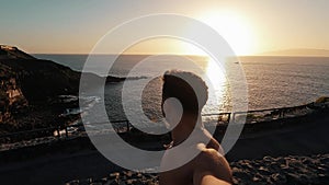 One happy and cheerful young man looking at the camera and walking at the beach alone with sunset at the background. Male person