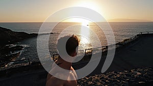 One happy and cheerful young man looking at the camera and walking at the beach alone with sunset at the background. Male person