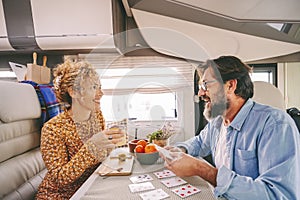 One happy couple enjoy time and have fun together inside camper van during travel lifestyle or holiday with vehicle. Man and woman