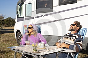One happy couple enjoy travel nomad tourism sitting at the outdoor table outside a camper van Renting vacation vehicle concept.