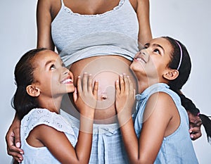 One happy family. two cheerful little girls standing next to their pregnant mother at home during the day.