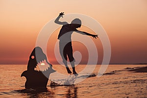 One happy little boy playing on the beach at the sunset time.