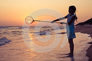 One happy little girl playing on the beach at the sunset time.