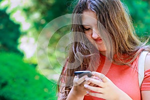 One happy student walking and using smart phone on line in the street at sunset with a warm light beautiful teen girl reading a me