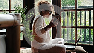 One happy woman listen music and dance sitting at hoe with phone and laptop on the ground. Nature green background outside nature