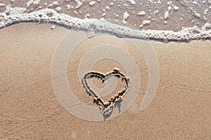 One Heart Drawn in the Sand on a Beach.soft wave of the sea.Romantic love. true love.Beige beach