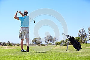 One heck of a drive. Rearview of a mature male golfer playing on shot on the golf course.