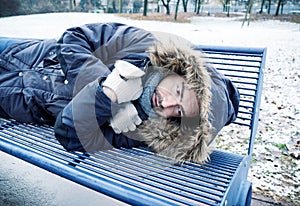 One homeless man alone suffering cold weather on a bench