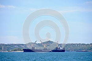 One huge logistic transportation ship with cranes to move cargos around floating in the ocean on sunny day photo