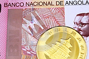 A one hundred Angolan kwanza bank note with a gold Chinese panda coin