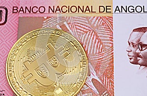 A one hundred Angolan kwanza bank note with a golden physical Bitcoin photo
