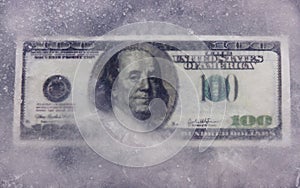 One hundred dollar banknote frozen in ice.
