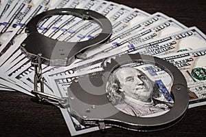 One hundred dollar bills and steel handcuffs close up