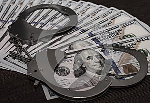 One hundred dollar bills and steel handcuffs close up