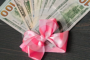 One hundred dollar bills wrapped in a pink ribbon