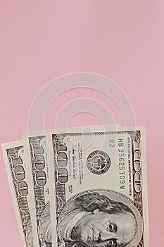 One hundred dollars banknotes on pink background. Flat lay, top view, copy space