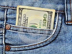 One hundred dollars bill in the pocket of blue jeans close up