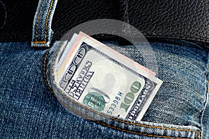 One hundred dollars bill sticking out of the blue jeans pocket