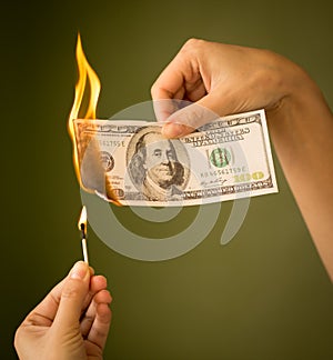 One hundred dollars burn with fire in their hands
