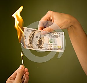 One hundred dollars burn with fire in their hands