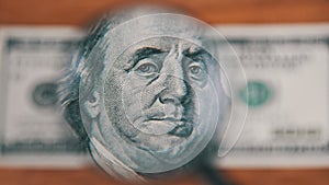 One Hundred Dollars Look Under Magnifying Glass on Wooden Table