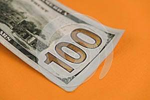 one hundred dollars lying on orange background close up