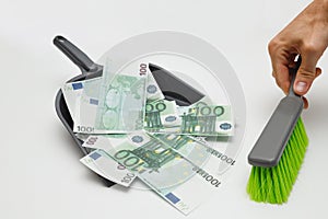 One hundred euro banknotes being swept with brush into rubbish dustpan. Euro currency depreciation