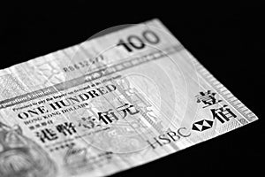 One hundred Hong Kong dollars banknote on a dark background. Black and white