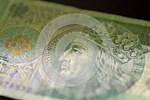 One hundred Polish zloty banknote on a dark surface close-up. Money background green color toned