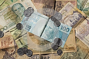 One hundred reais current brazilian currency displayed at the top of former currencies of Brazil with coins photo