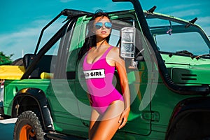 One incredible tan beautiful young girl in bikini swimsuits, traveling around a tropical island in a cabriolet off-road car summer