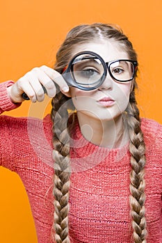 One Intelligent Caucasian Girl in Glasses And Coral Knitted Sweater Holding Big Magnifying Glass While Searching And Looking