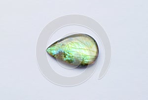 One iridescent drop-shaped labrodarite cabochon on a white background. Beautiful semi-precious stone for jewelry. Stone for