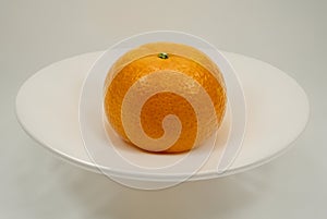 One isolated orange on a white plate