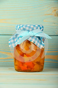 One jar of quince jam at blue vintage wood surface