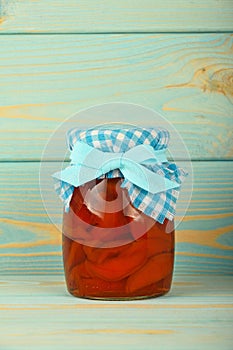 One jar of quince jam at blue vintage wood surface