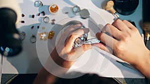 One jeweller uses pliers to tighten a ring. Jeweler, goldsmith in a professional jewelry workshop.