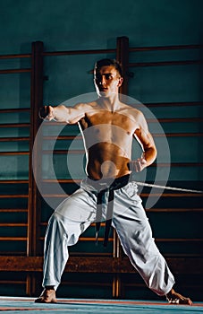 One judoka fighter man in kimono pants practicing in the gym