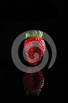 One juicy strawberry on black background