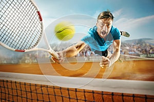 The one jumping player, caucasian fit man, playing tennis on the earthen court with spectators